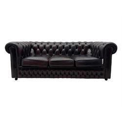 Chesterfield three-seat sofa, traditional shaped upholstered in deeply buttoned dark red leather; together with similar footstool 