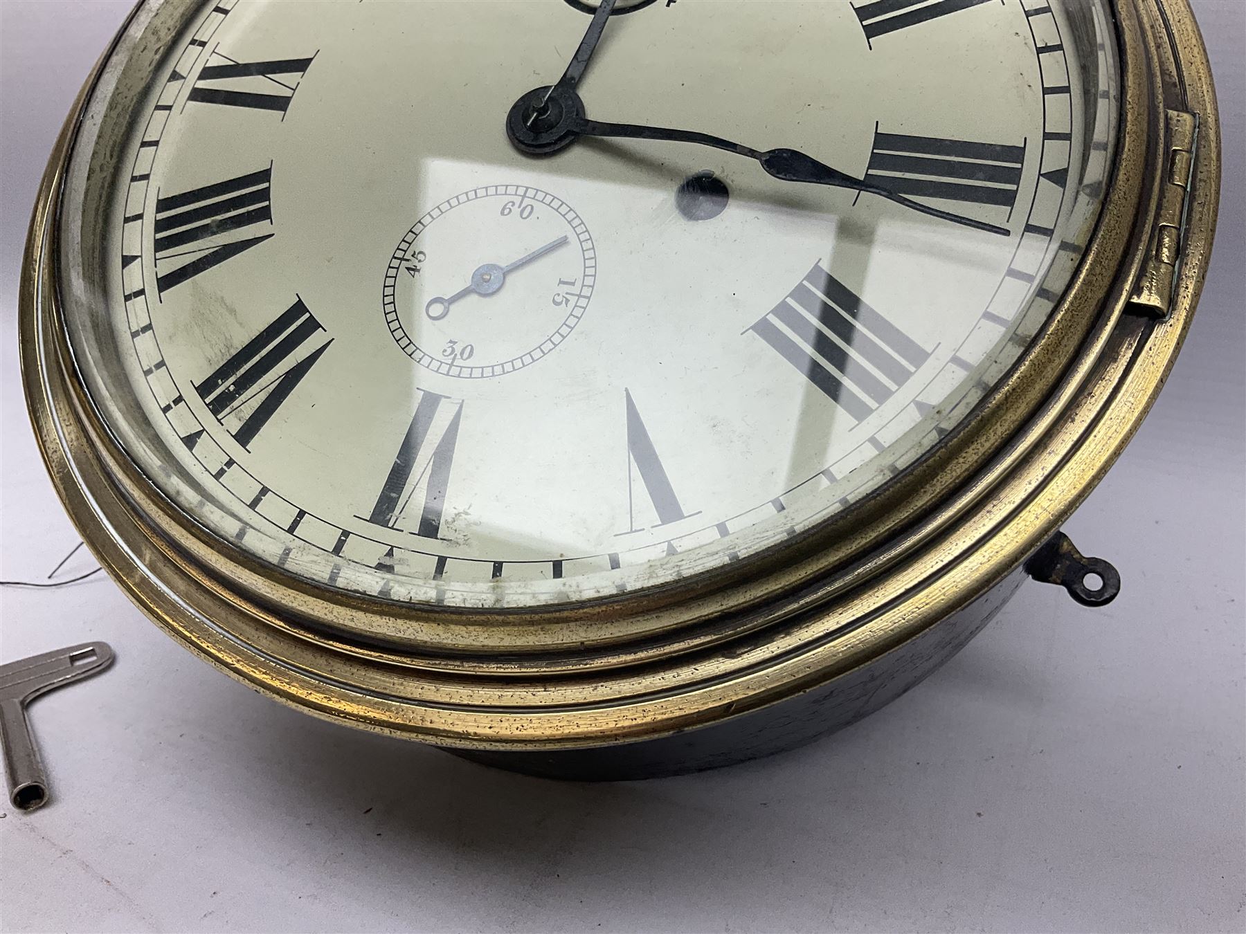 Seth Thomas ship's bulkhead clock with brass bezel and japanned case, the white dial with Roman numerals and subsidiary seconds dial D23.5cm; with key