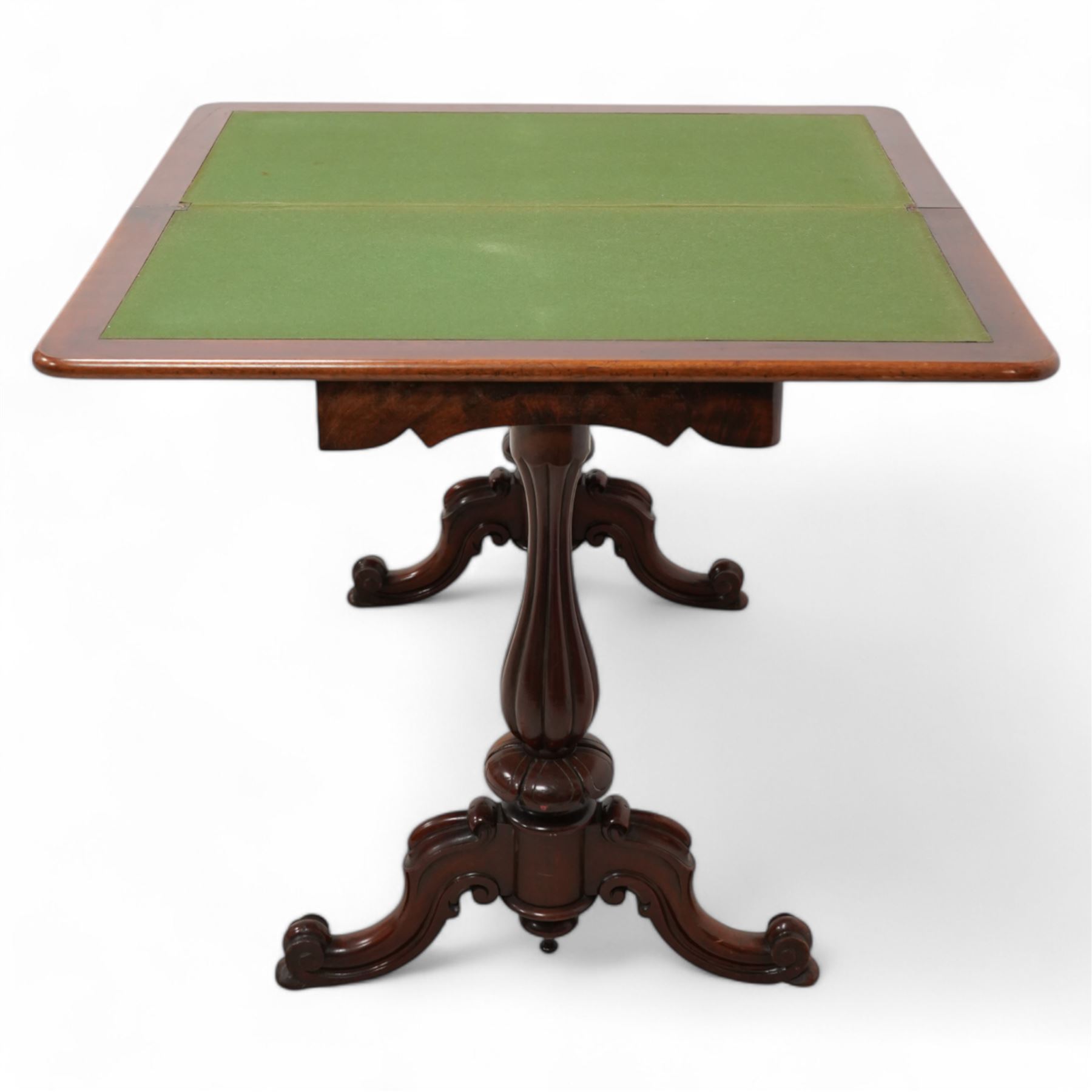 Victorian figured mahogany card table, rectangular swivel and fold-over top with rounded corners and baize lined interior, shaped apron over turned and lobe carved end supports, terminating to scroll and cartouche carved splayed supports united by swell-turned stretcher