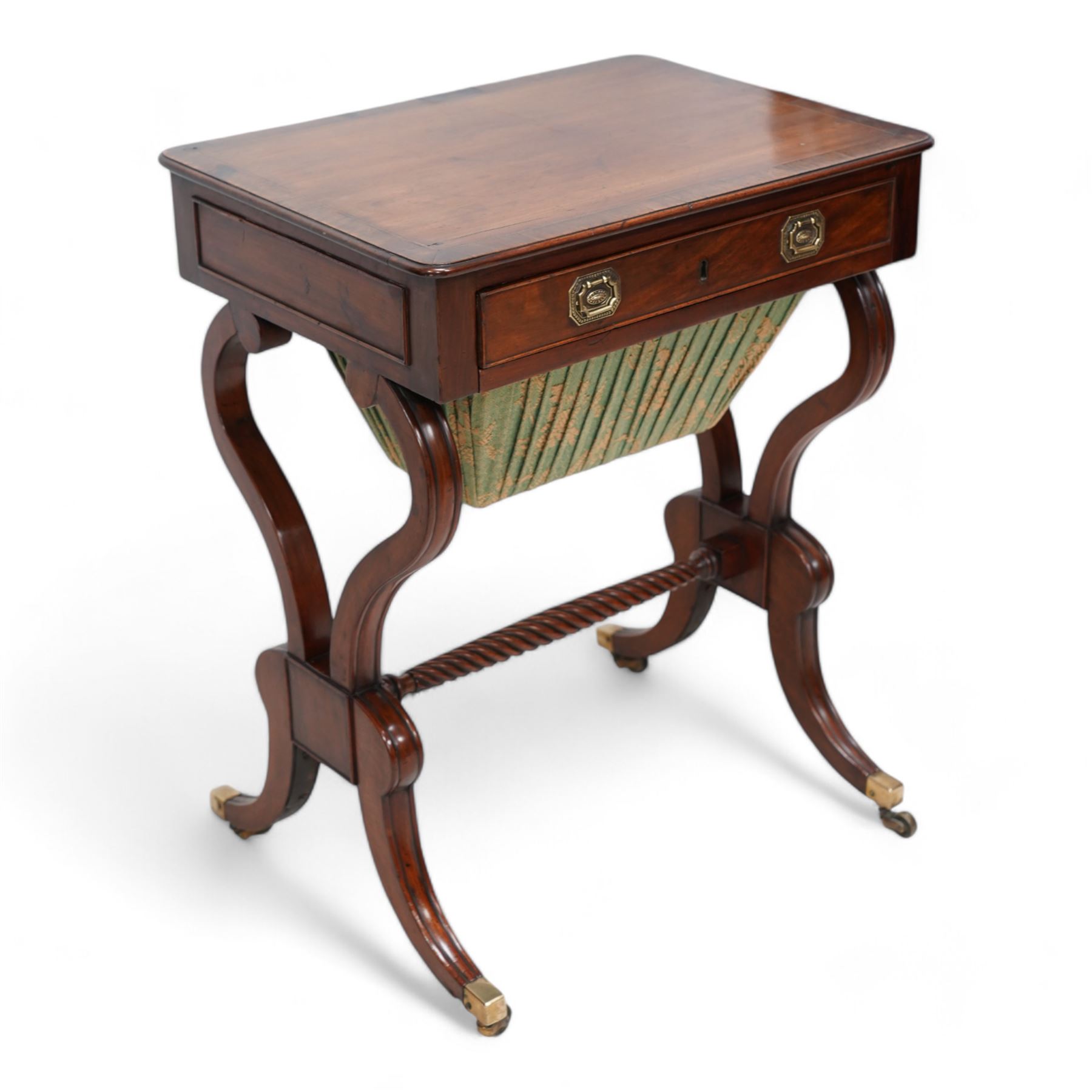 Regency mahogany work table, rectangular top with banded and moulded edge inlaid with checkered stringing, fitted with single cock-beaded drawer over upholstered sliding well, raised on scrolled twin end supports, united by a spiral-turned stretcher, on splayed supports with brass cups and castors