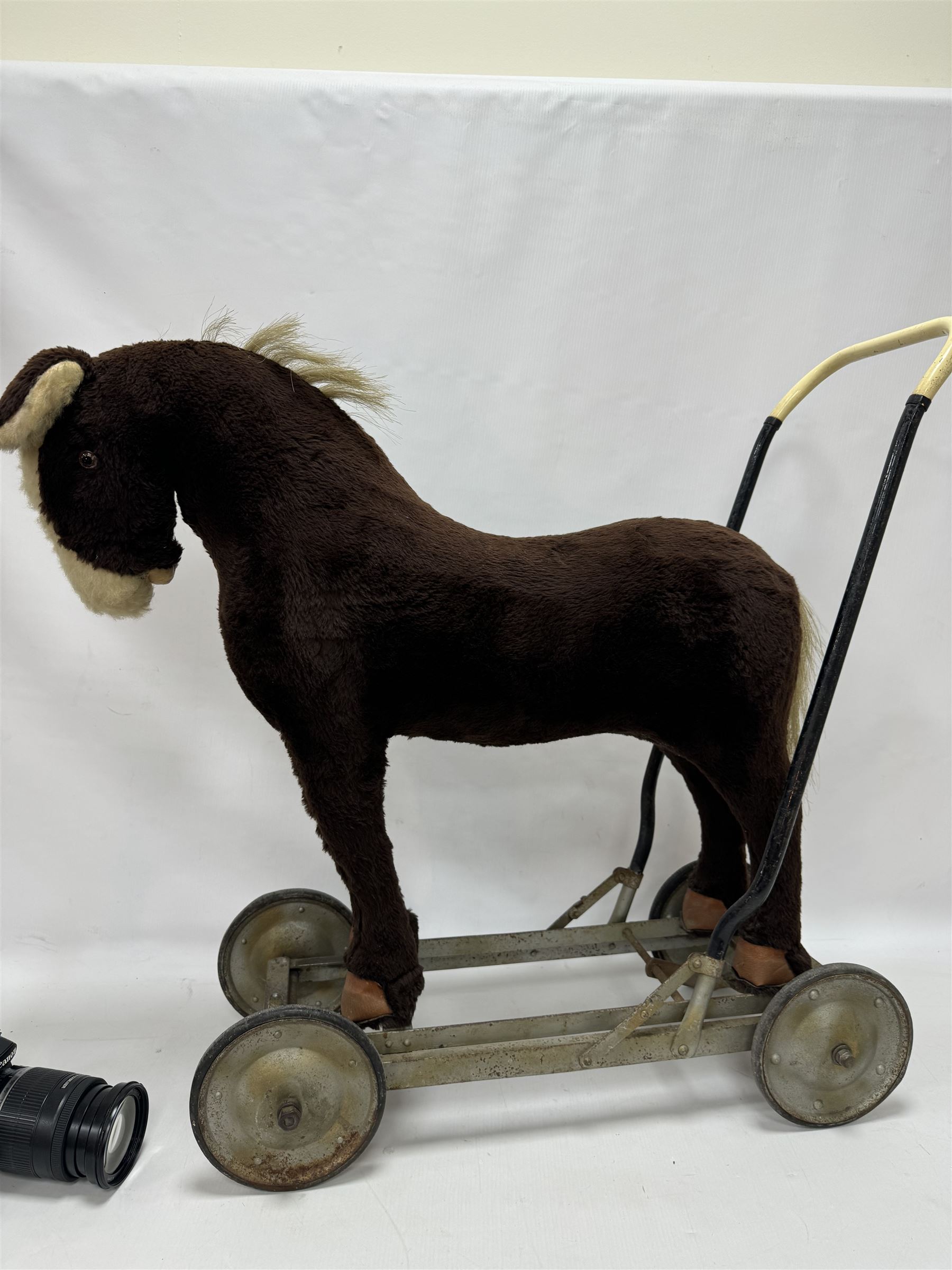 1920s/30s Panurge Pets push-a-long horse, with brown mohair body and white face, horse hair mane and tail and leather hooves, mounted upon a metal with rubber and metal wheels, including handle H71cm