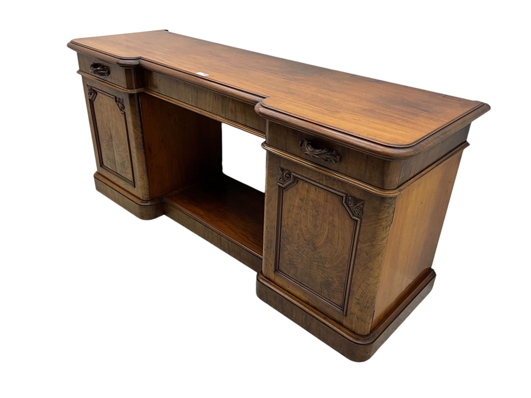 Mid-19th century figured mahogany sideboard, moulded reverse-break front, fitted with three drawers and two cupboards, carved faux bois handles, enclosed by panelled doors with book-matched veneers, applied geometric mouldings and scroll leaf decoration, on moulded plinth base 