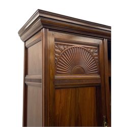 Late Victorian walnut triple wardrobe, projecting moulded cornice over central bevelled mirror door and flanking panelled doors, the top panels carved with fluted fans and stylised leaf motifs, the interior fitted with three linen slides, two drawers and hanging space, two long drawers to base, reed moulded uprights and vertical fluted horizontal rails 