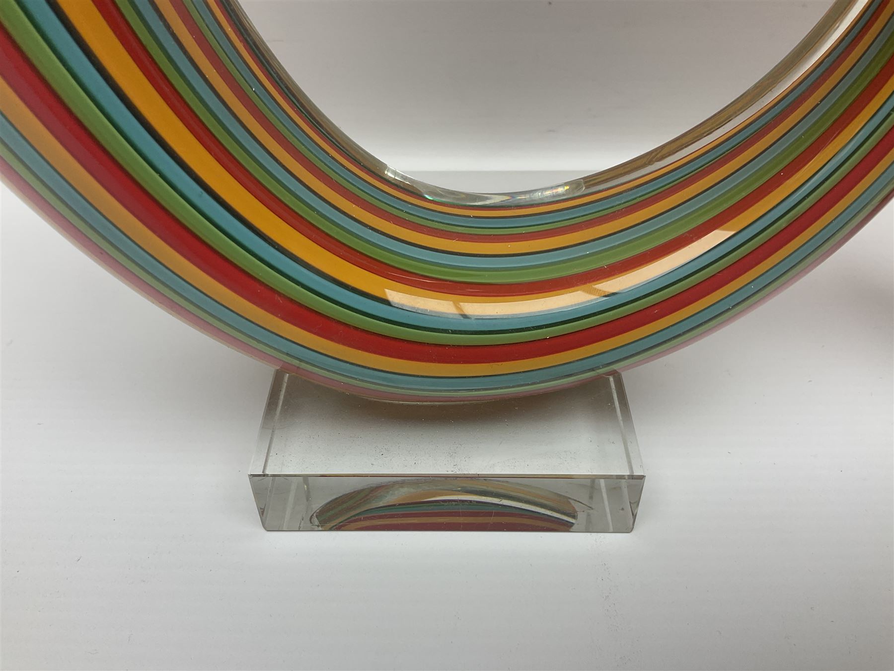 Three art glass sculpture, coiled form with multicolour stranded, upon clear glass plinth, unsigned, largest H27cm