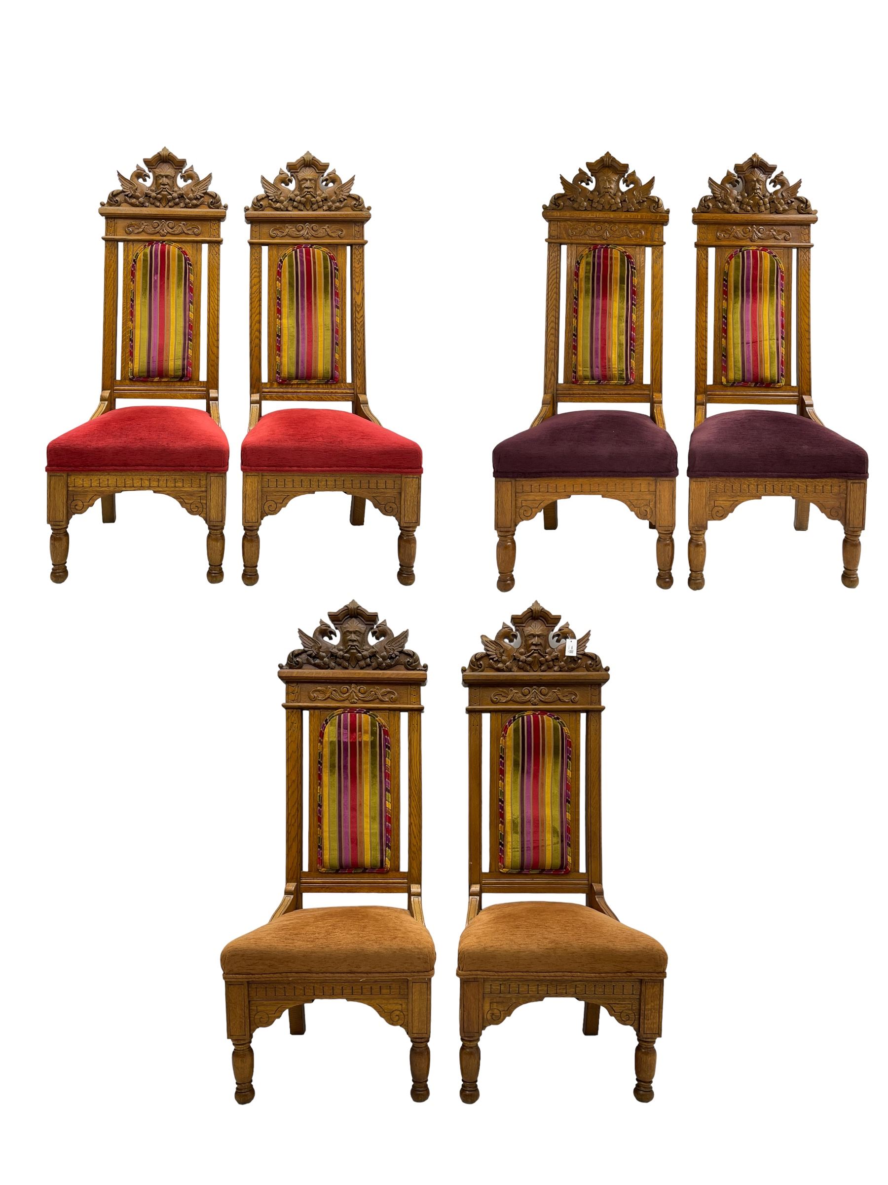 Set of six 20th century Carolean design oak high back chairs, the pediment carved with dragons and central Green Man mask with trailing foliage, the backs upholstered in striped fabric, on turned front supports