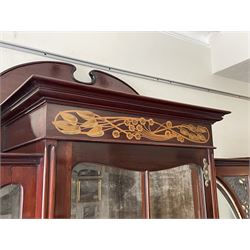 Art Nouveau period inlaid mahogany display cabinet, raised shaped and moulded pediment over projecting moulded cornices, the upper frieze inlaid with trailing branches and tulips, single astragal and bevel glazed door enclosed velvet lined interior fitted with shelves, flanked by curved glass panes decorated with pierced metal foliate spandrels, lower flanking shelves with mirror backs enclosed within shaped and pierced rails inlaid with flower heads, on tapering octagonal supports terminating to compressed pad feet, the lock stamped 'Salmon Bros, London' 