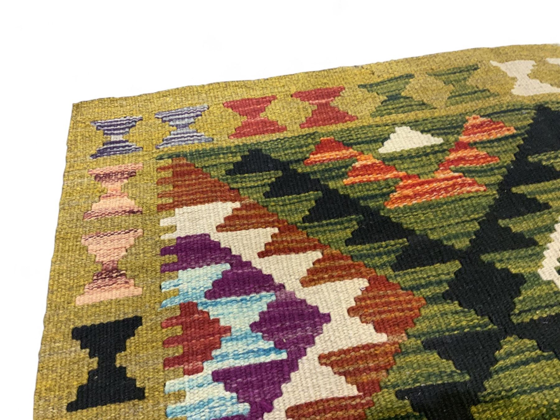 Chobi kilim multi-coloured rug, the field decorated with various lozenges with dark indigo borders, enclosed by a guard band with repeating broken-lozenge design