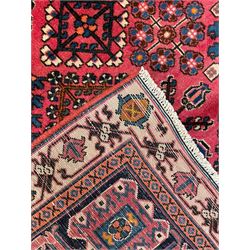 Persian Joshaghan red ground rug, the medallion, field and spandrels decorated with Pitrak and tree of life motifs, the border with repeating design decorated with stylised plant motifs, within guard stripes