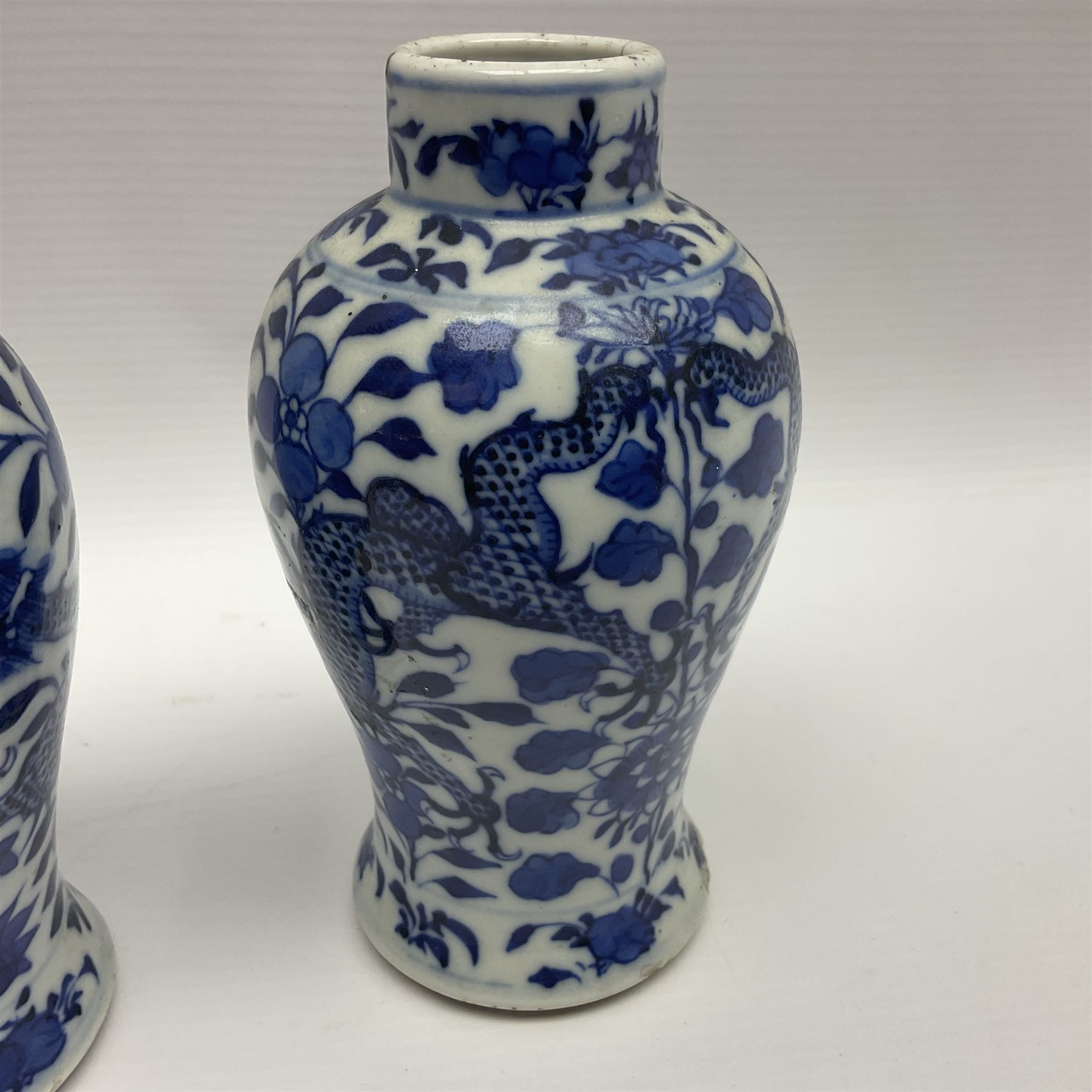 Pair of late 19th/early 20th century Chinese blue and white vases, each of baluster form, painted with dragons amidst flowers, each with Kangxi character marks beneath, H14cm 