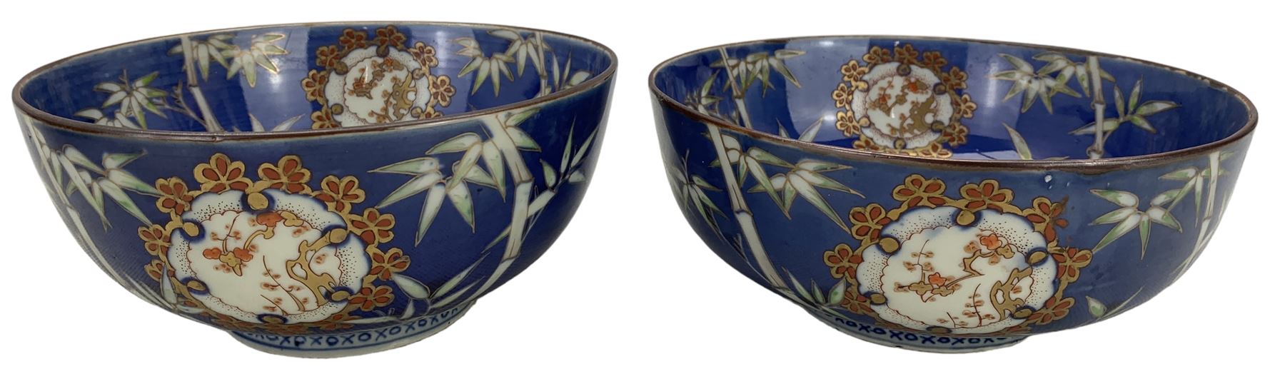 Set of four Japanese graduating porcelain bowls, each centrally painted with a coiled dragon in reserves, bamboo and foliate roundels against a blue ground, largest measuring D24.5cm (4)