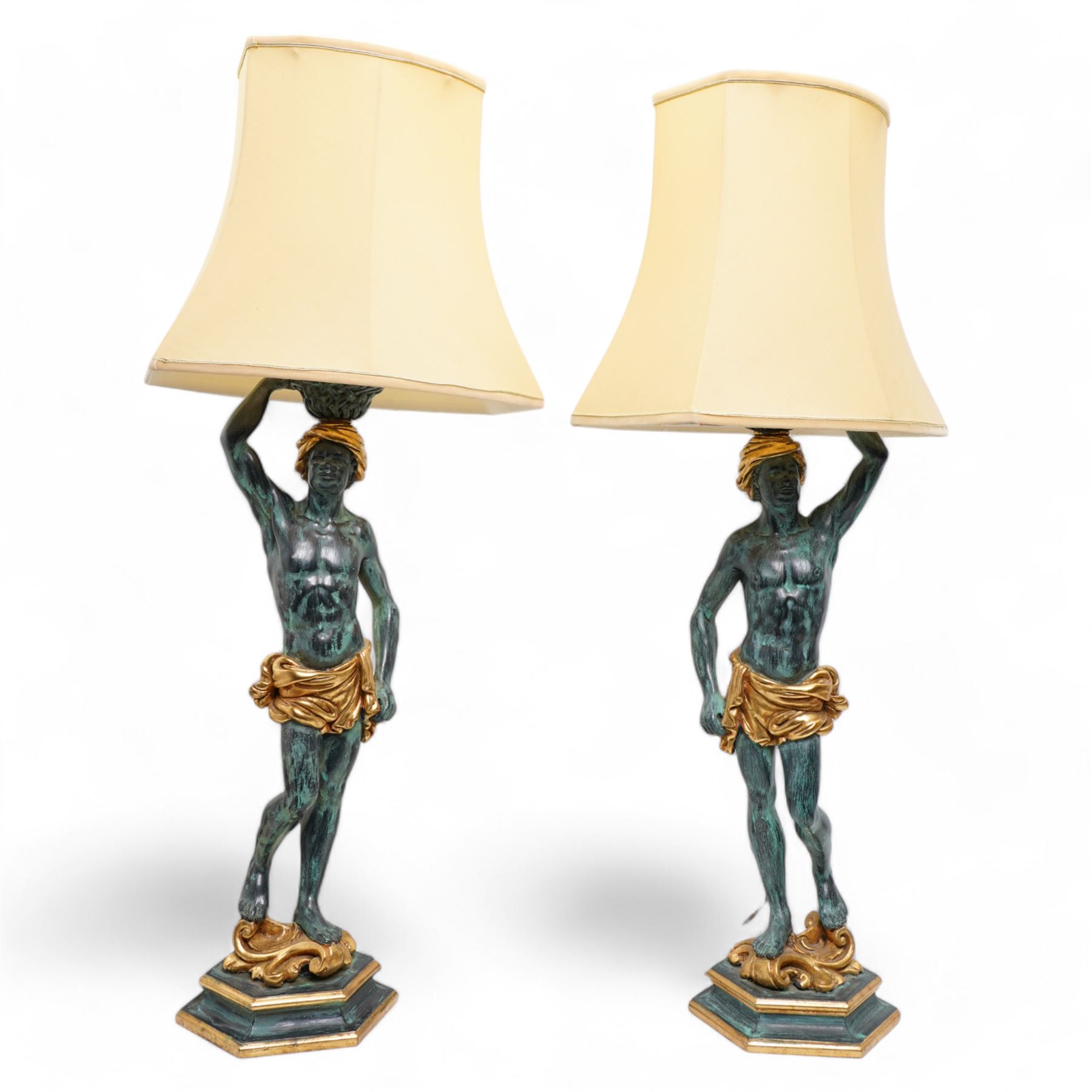 Pair of Italian figural carved table lamps, each modelled as a semi-nude male figure holding a basket above their heads, with green patinated and gilt decoration, on hexagonal bases, H68cm excluding fitting