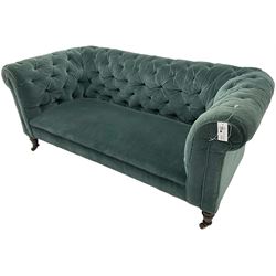 Victorian hardwood-framed Chesterfield sofa, traditional shape with low back and rolled arms, upholstered in teal buttoned fabric, on turned front feet with brass and ceramic castors 