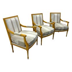 Three mid-20th century beechwood fauteuil armchairs, upholstered backrest and seat in cream stripe fabric, padded armrests with scroll detail, on tapered fluted supports with carved floral rosette blocks