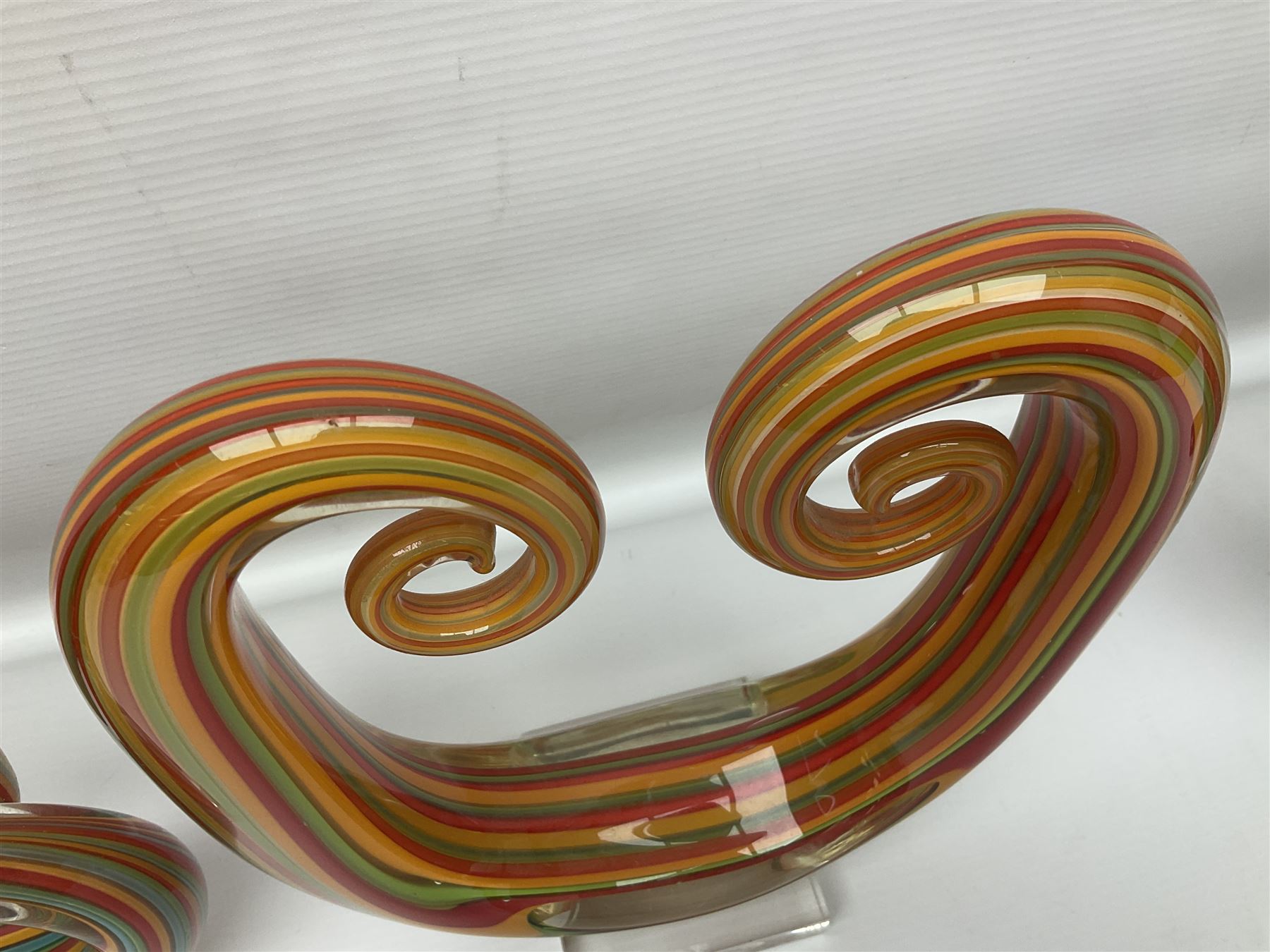 Three art glass sculpture, coiled form with multicolour stranded, upon clear glass plinth, unsigned, largest H27cm