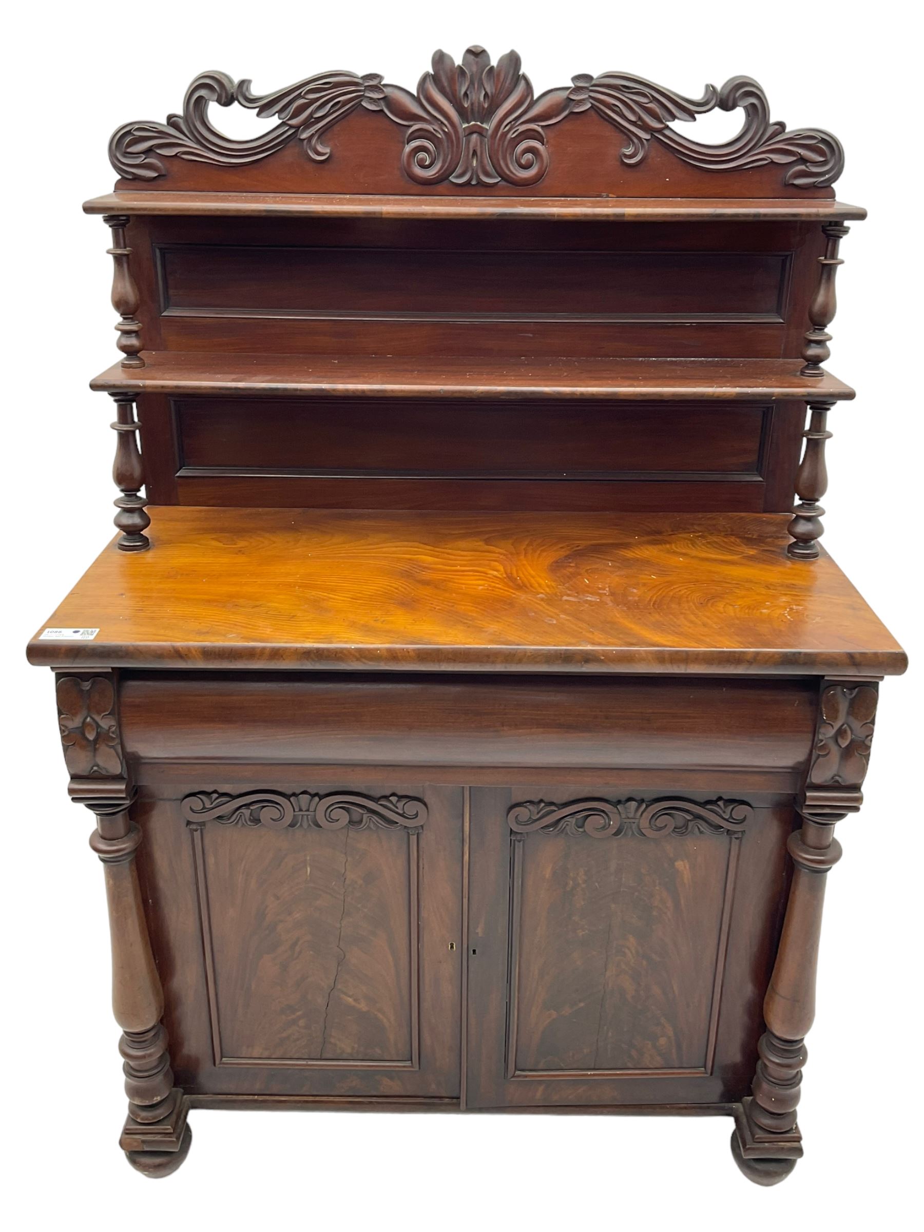 Victorian mahogany chiffonier, raised shaped pediment carved with scrolled extending foliage, two graduating shelves on turned supports, rectangular top over drawer and double cupboard, turned column pilasters, on turned feet 