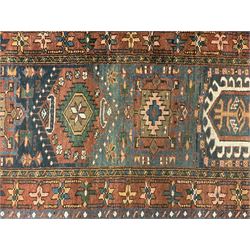 Antique Turkish Heriz red ground runner rug, field decorated with seven central geometric medallions, multi-band border with repeating stylised plant motifs