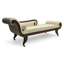 Regency design mahogany chaise longue, scrolled arms with carved rosette details, upholstered in cream damask fabric with bolster cushion, reeded frame supported by turned legs on brass castors