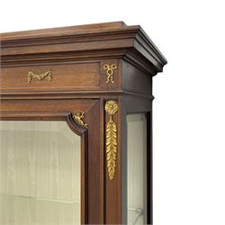 Early 20th century Louis XVI design mahogany vitrine display cabinet, projecting stepped cornice over recessed frieze decorated with gilt metal mounts of festoons and a bellflower wreath, fabric lined interior with two glass shelves, enclosed by bevel glazed door with lower panel, on two turned front feet 