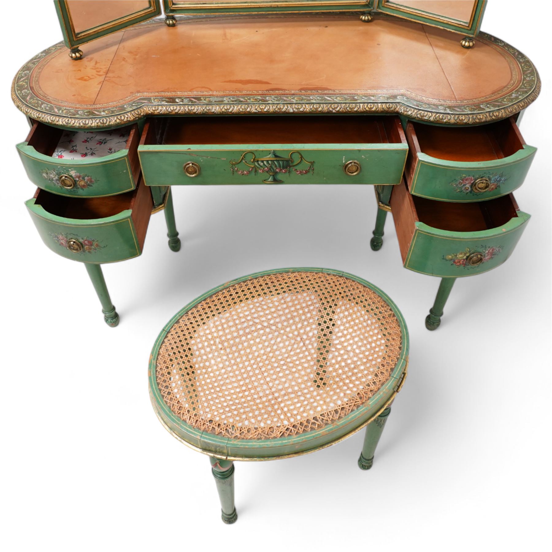 Edwardian Adam Revival green-painted and parcel gilt kidney-shaped dressing table, raised triple mirror back with shaped cresting, leather inset top within a trailing floral painted band and foliate carved edge, fitted with five drawers decorated with urn and floral bouquets, on turned supports painted with acanthus leaves and draped festoons; together with matching stool with cane seat 