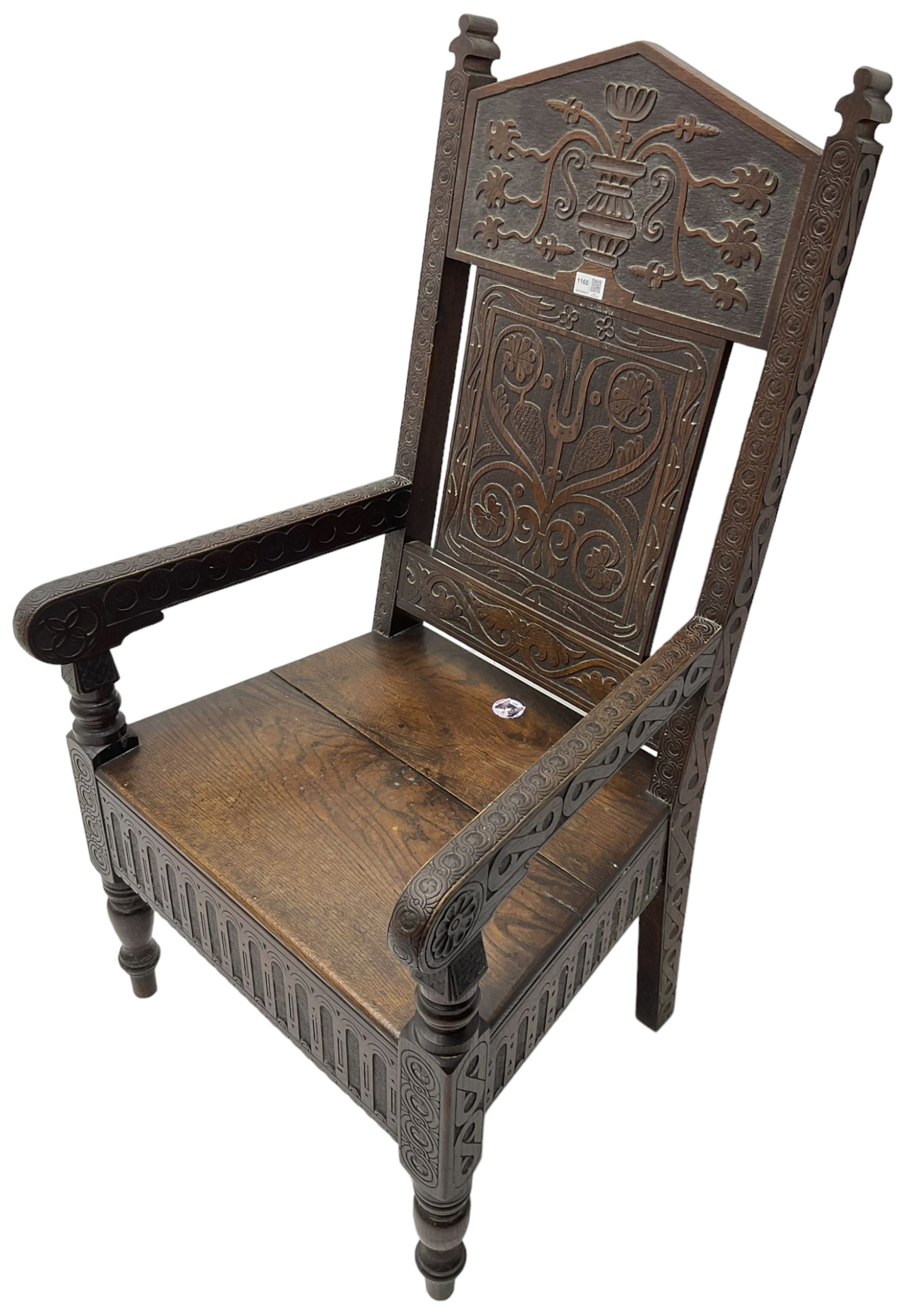 17th century design oak wainscot chair, the back profusely carved with scrolling foliate motifs, the arms carved with repeating guilloche decoration over an arcade apron and turned supports