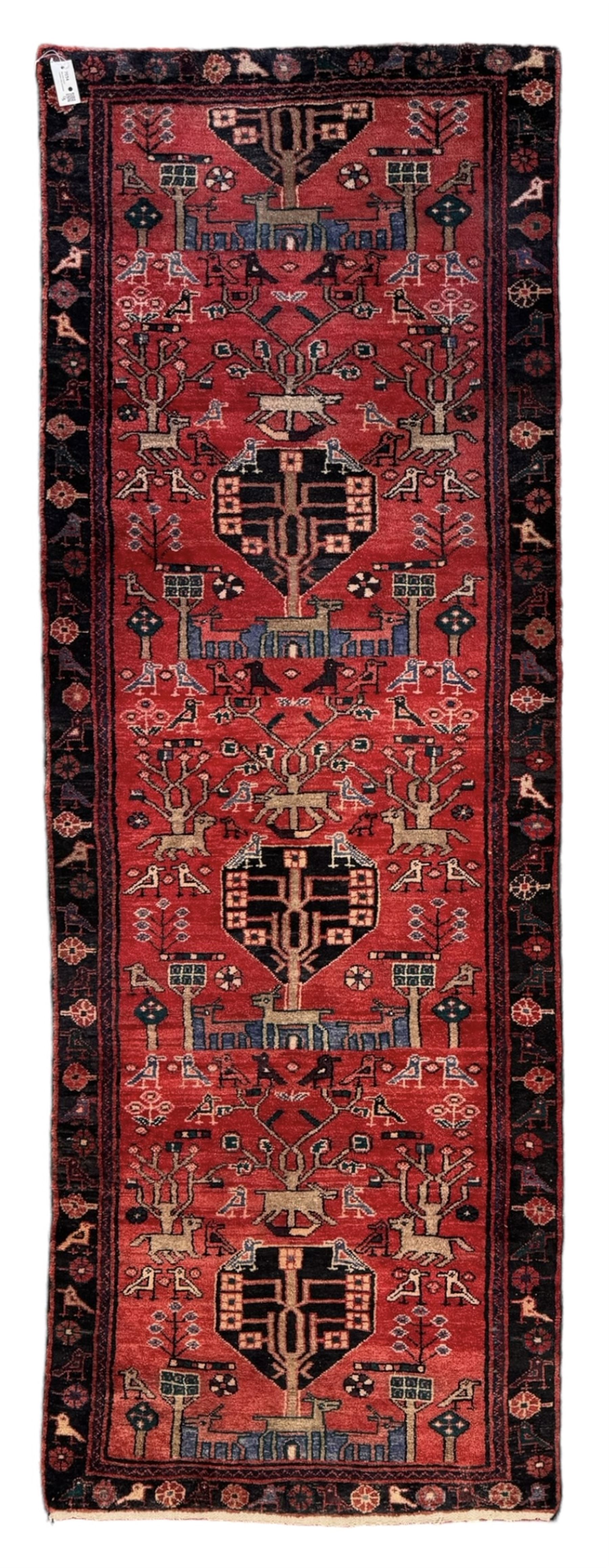 Persian crimson ground runner, the field decorated with stylised tree and animal motifs, indigo ground border decorated with alternating stylised flowerhead and bird motifs 