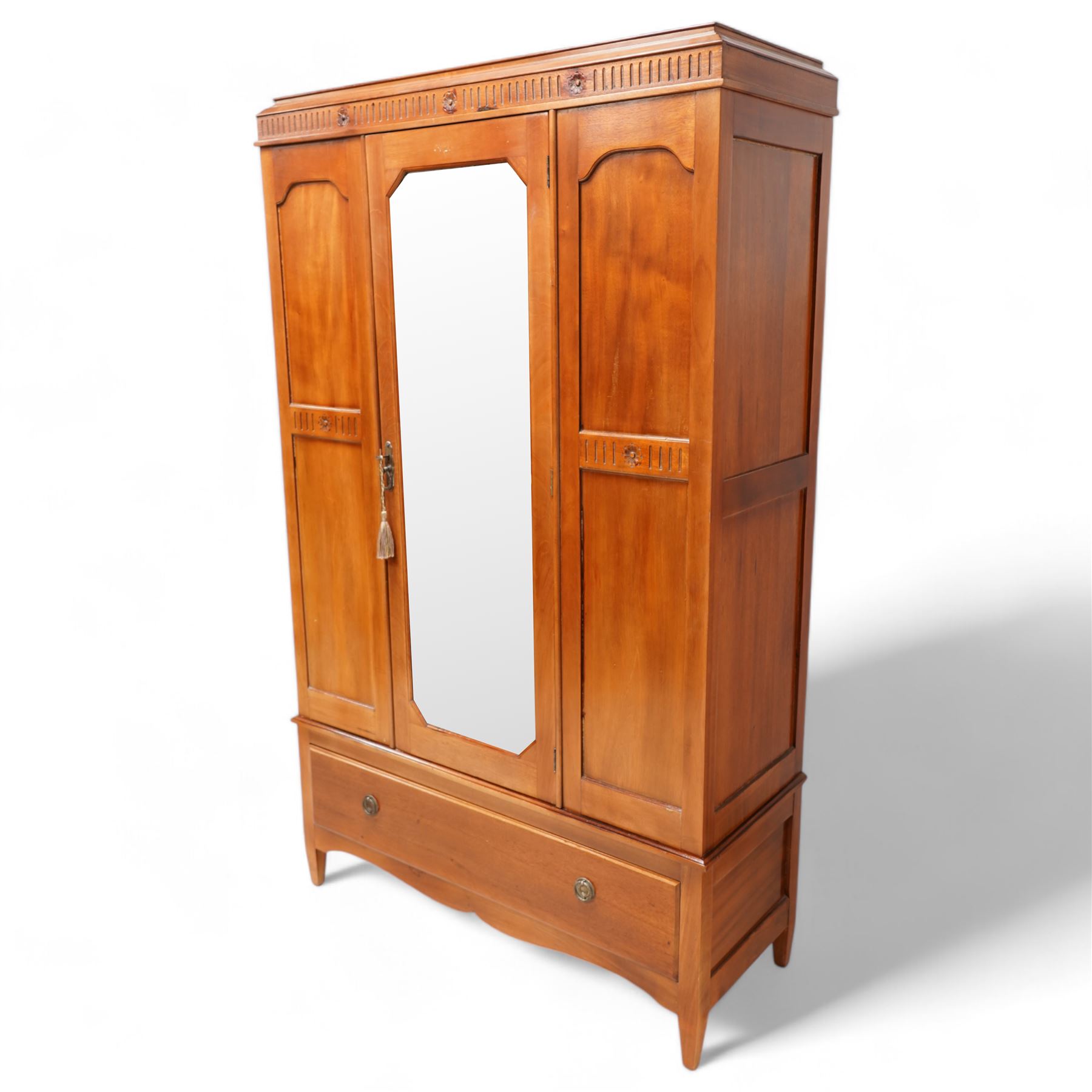 Early 20th century mahogany three piece bedroom suite - comprising a triple wardrobe (W119cm D47cm H194cm); chest with raised back, fitted with four long drawers (W93cm D49cm H115cm); and dressing table with swing mirror back (W108cm D49cm H152cm), each decorated with rosette and fluted designs, on square tapering feet