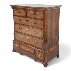 George III oak and mahogany banded chest on stand, moulded cornice over two short and three long drawers, shaped brass handle plates and swan neck handles, enclosed by canted corners with turned quarter columns, the stand fitted with three drawers, on bracket feet