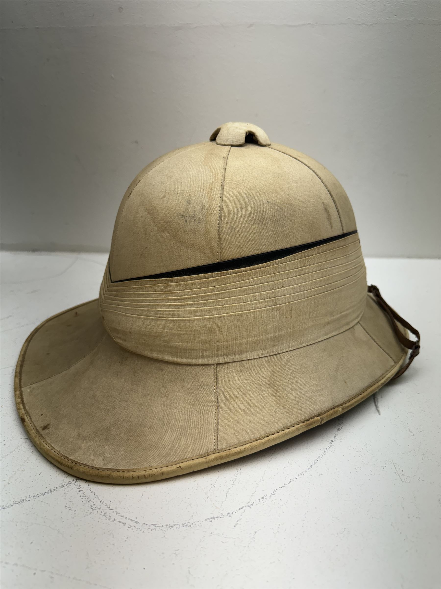 WWII Royal Navy officers sun helmet with large folded pagri and black top line, interior with green cloth covering to the peaks and original leather sweatband, with makers label 'Gieves Ltd London', with its original storage tin with indistinct painted lettering to the front 