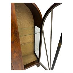 Early 20th century Art Deco walnut display cabinet, with arched top and carved floral crest, central band flanked by two glazed panel doors with decorative mullions, enclosing two glass shelves, on scroll carved bracket feet