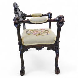 19th century Italian heavily carved stained walnut open armchair, the back rail carved with a large central cartouche decorated with extending acanthus and C-scroll motifs, the wing and arm terminals carved in the form of snarling dog masks, seat upholstered in floral needlework, shaped apron carved with cartouche and shell motifs, over out-splayed cabriole supports with acanthus moulding, terminating to paw feet