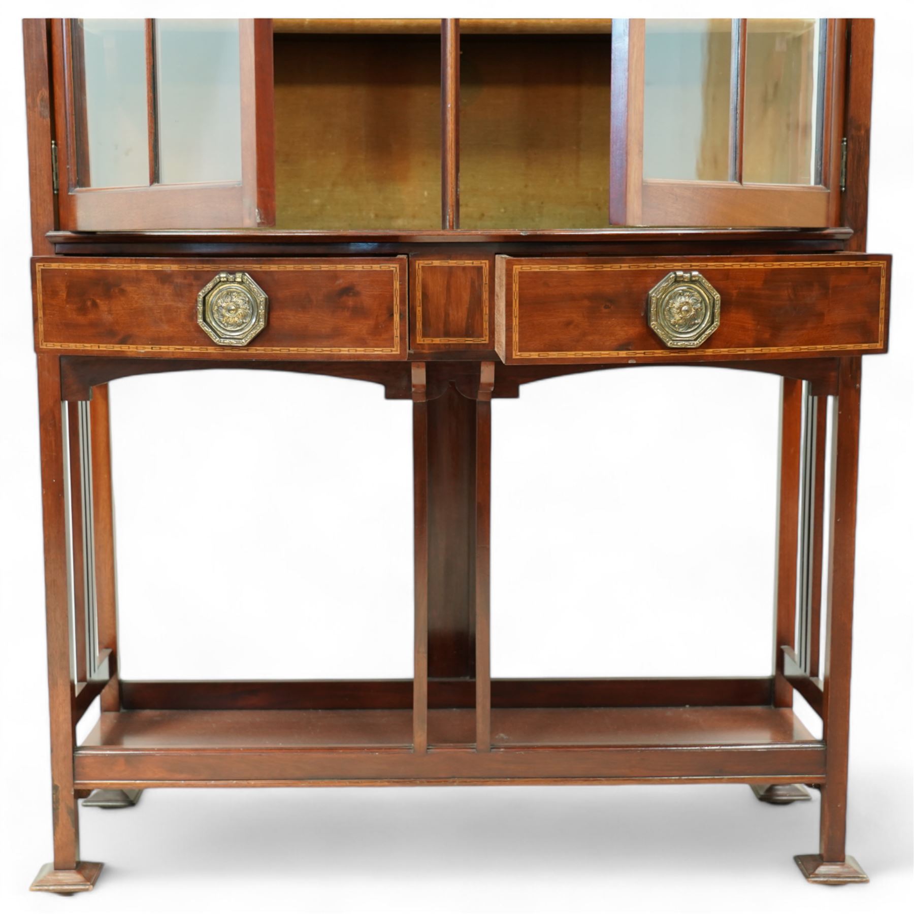 Edwardian mahogany glazed display cabinet, projecting cornice over astragal glazed doors enclosing three velvet lined shelves, over two bow-front drawers with Tunbridge Ware style inlaid stringing, on pierced end supports united by undertier