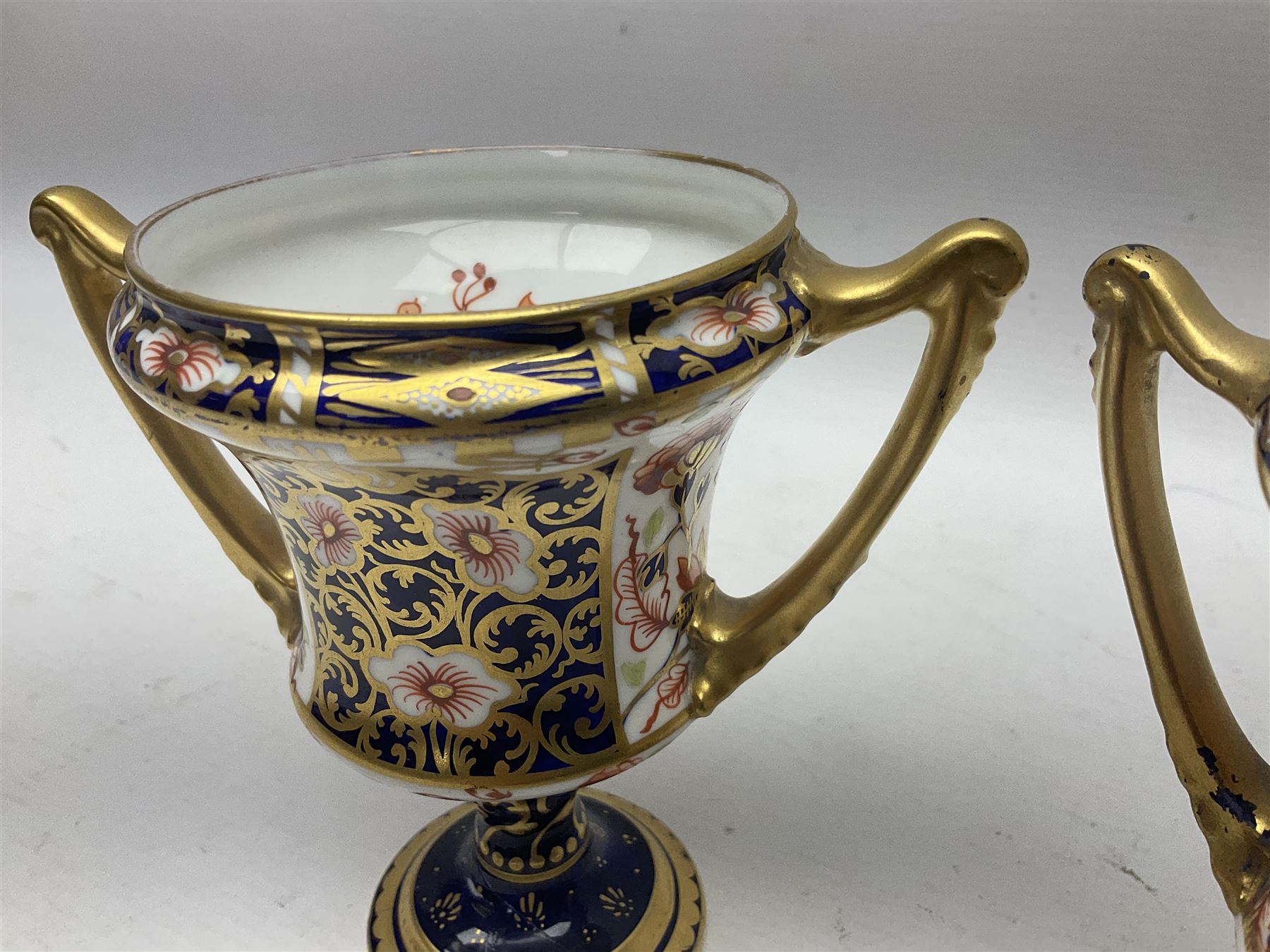 Pair of Royal Crown Derby 6299 Imari pattern twin handled trophy vases, of wasted cylindrical form, with printed mark beneath, H13cm 