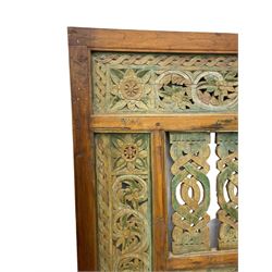 Early 20th century Javanese teak and hardwood door panel or room divider, rectangular panelled form with moulded frame and pegged construction, carved and pierced with scrolling decoration and flower head motifs, shaped and pierced splats with interlocking pattern