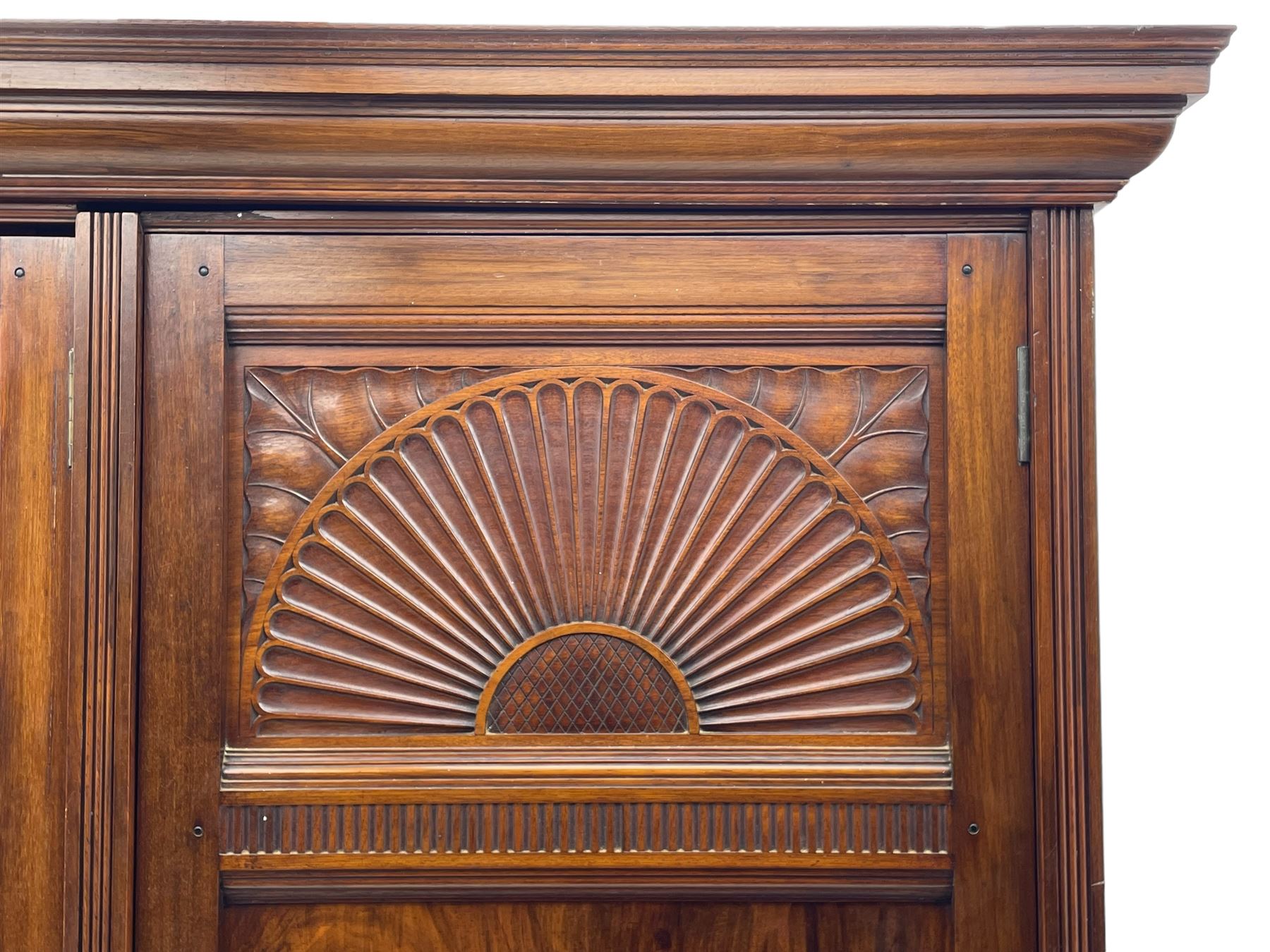 Late Victorian walnut triple wardrobe, projecting moulded cornice over central bevelled mirror door and flanking panelled doors, the top panels carved with fluted fans and stylised leaf motifs, the interior fitted with three linen slides, two drawers and hanging space, two long drawers to base, reed moulded uprights and vertical fluted horizontal rails 