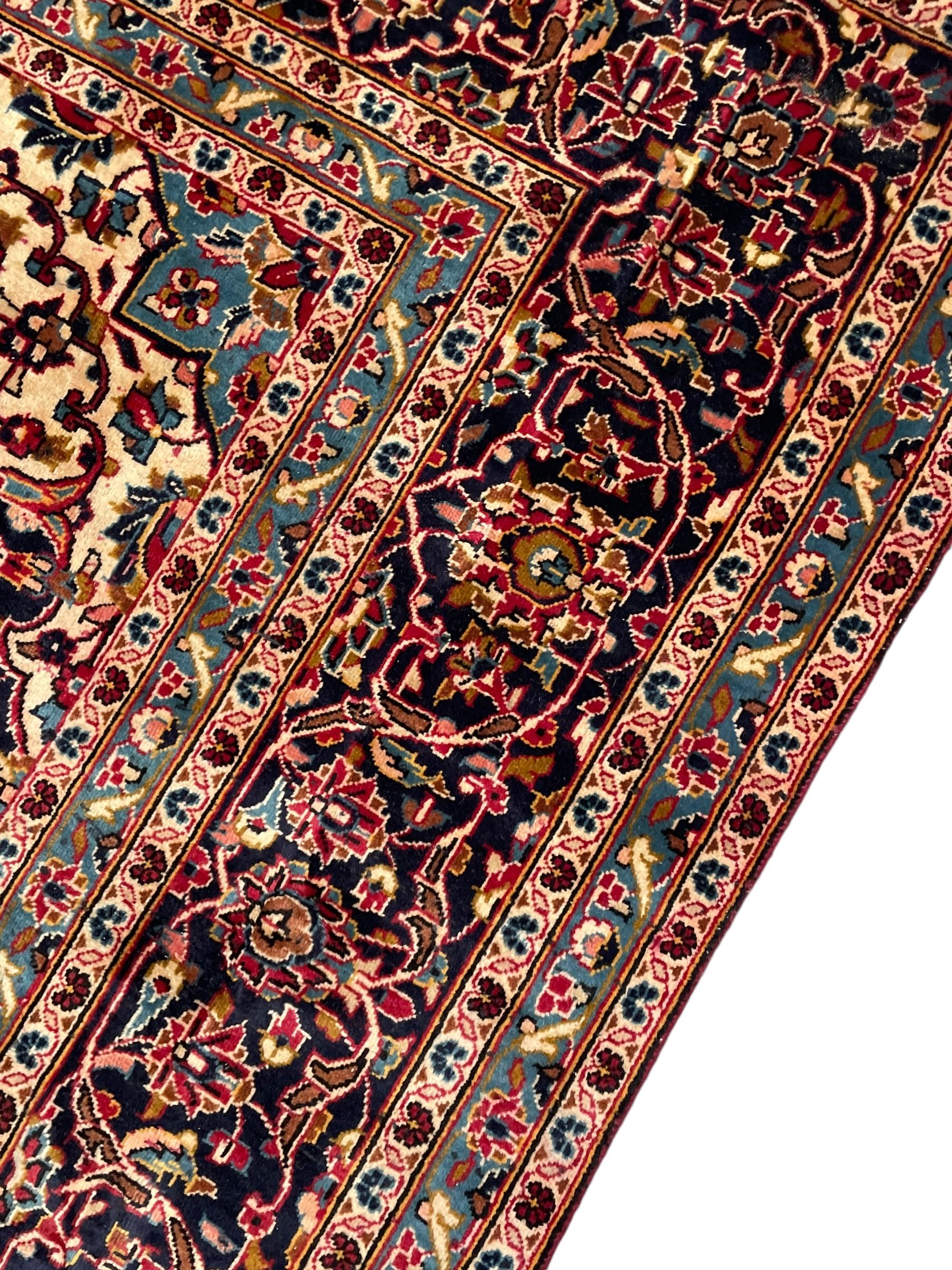 Persian Kashan crimson ground carpet, floral pattern pole medallion surrounded by trailing branches with foliate motifs and palmettes, scrolling border decorated with stylised plant motifs, within multiple guard stripes