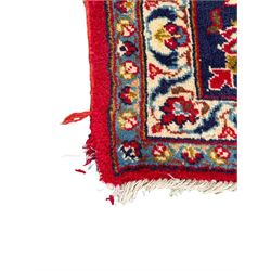 Persian Kashan red ground rug, the field decorated with a central floral medallion surrounded buy scrolling vine motifs and palmettes, the main border featuring a series of stylised floral motifs against a dark blue ground, enclosed by multiple guard stripes with alternating floral and geometric designs