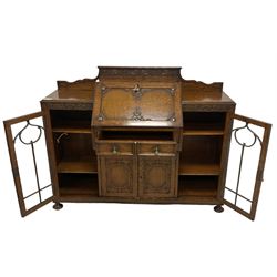 Early 20th century heavily carved oak bookcase bureau, raised back with grape-vine carved frieze, over fall-front enclosing fitted interior, above two short drawers and curved frieze drawer, flanked by astragal glazed and panelled cupboards, on turned feet