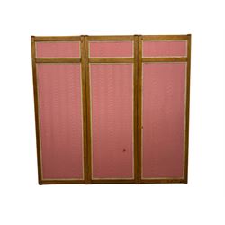 Edwardian oak and fabric folding screen, featuring three panels with oak frames, one side covered in green striped fabric with decorative trim, the reverse side in pink moiré effect fabric, connected by brass hinges