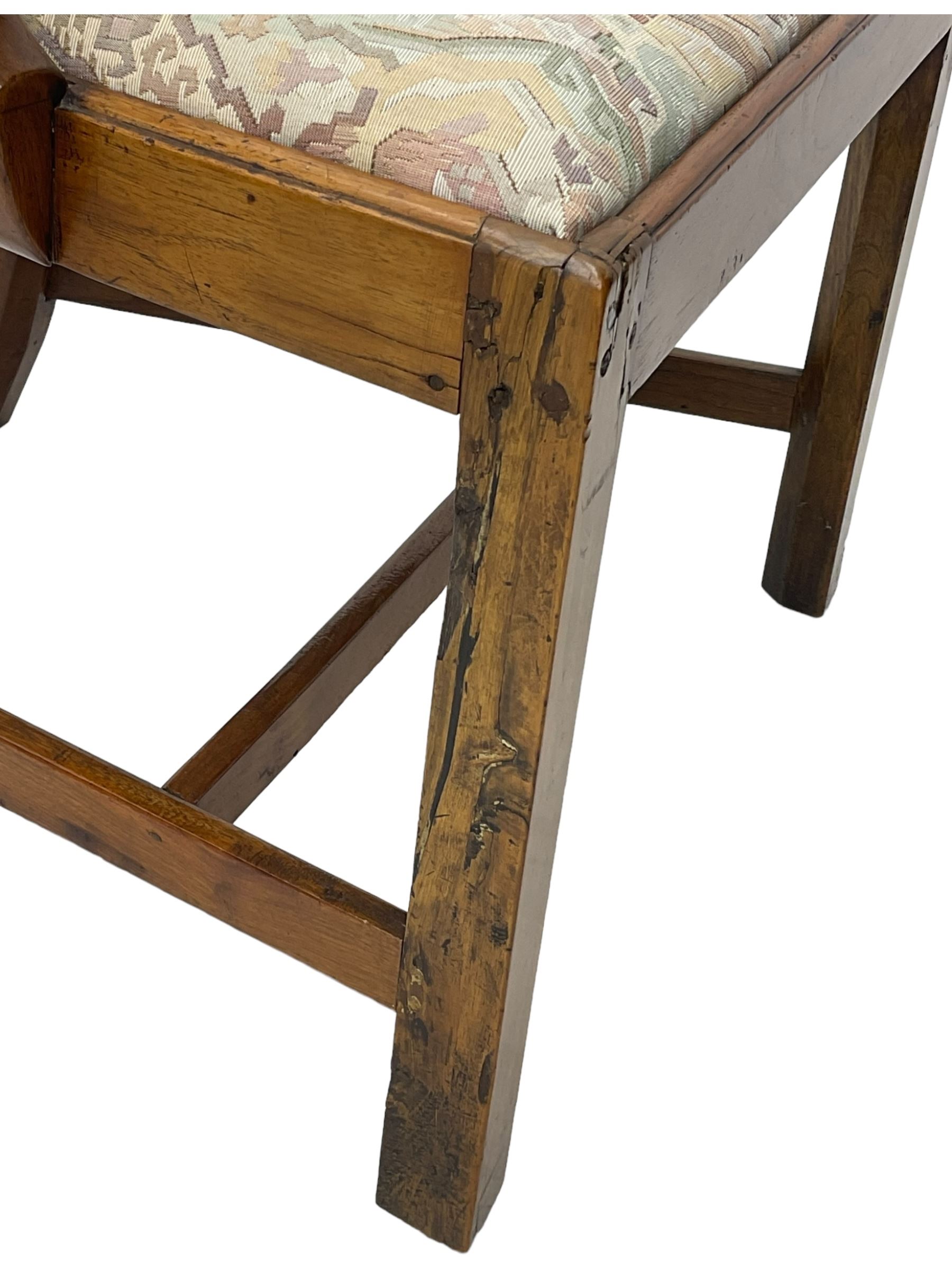 George III walnut elbow chair, shaped cresting rail over shaped pierced splat, the shaped arms with scroll carved terminals, upholstered drop in seat, on square chamfered supports united by plain stretchers 