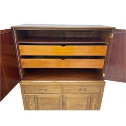 Early 20th century inlaid mahogany cabinet, two-door upper section revealing interior shelving and two large pull-out drawers, the lower section comprises two wide drawers flanked by inlaid floral motif panels above a double-door cupboard, supported by tapering legs with brass castors