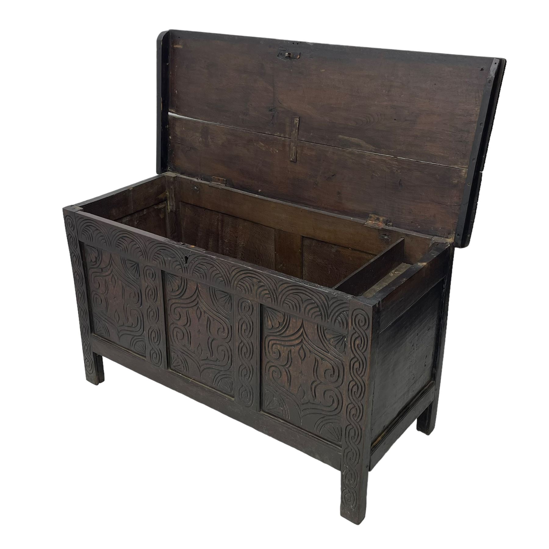 18th century oak blanket box, moulded and chip carved hinged lid, lunette carved cresting rail over triple panelled front carved with stylised leaf and scroll decoration, interlocking S-scroll carved upright rails, panelled sides and back, on stile supports 