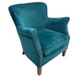 Contemporary tub-shaped armchair, upholstered in teal blue fabric, with high back and rolled arms accented with brass studded trim, on square tapered front feet