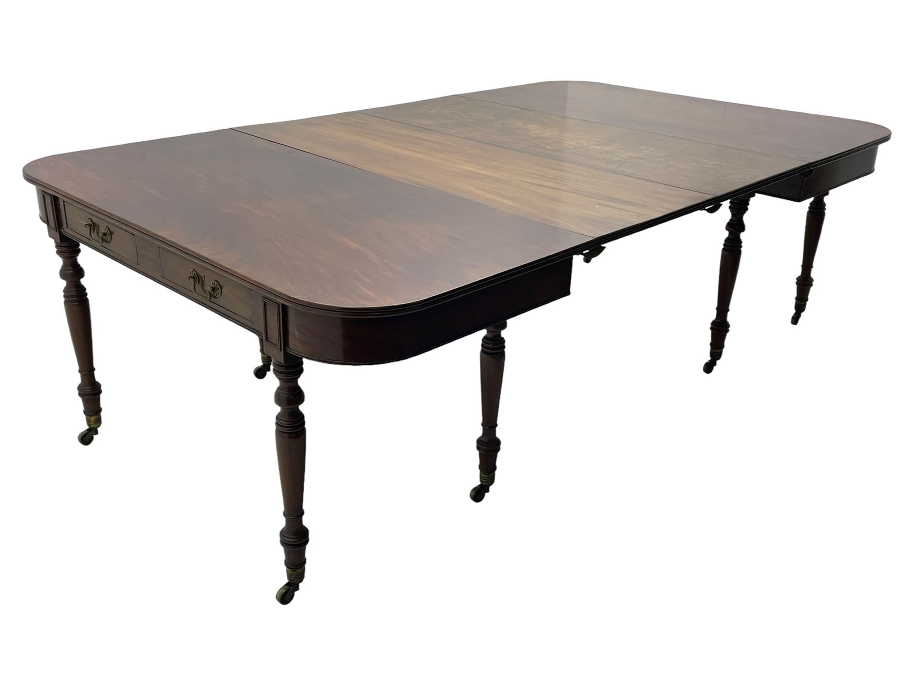 George III mahogany extending dining table, reed moulded rectangular top with rounded corners, two D-ends each fitted with two drawers, two additional leaves, on turned supports with ribbed brass cups and castors 