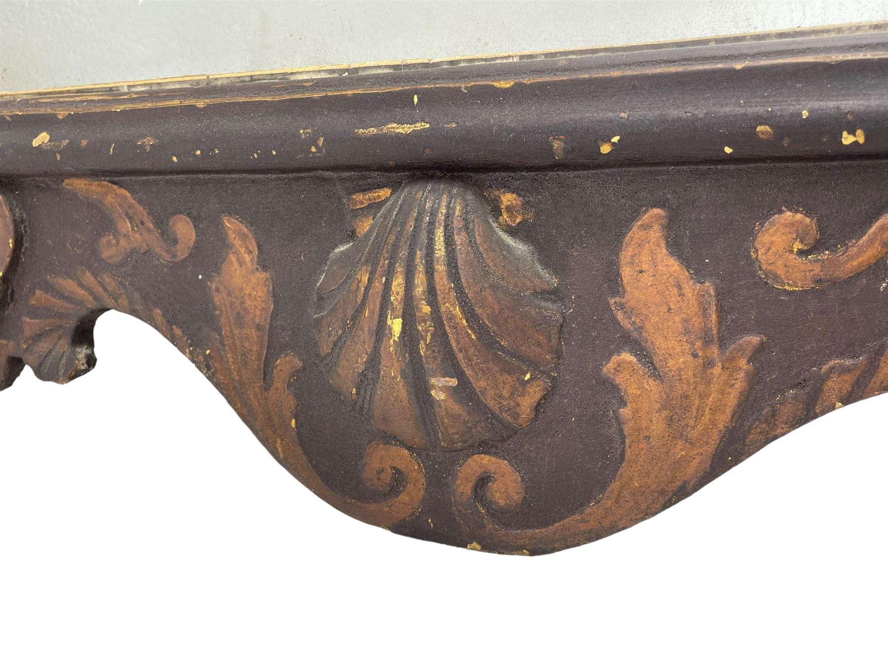 18th century black lacquered and gilt wall mirror, broken arch pediment with central cartouche decorated with curled leaves and foliate motifs, scrolled acanthus leaf eared brackets, bevelled mirror plate within gilt slip and moulded outer frame, lower shell motif surrounded by curled acanthus leaves and shield motifs 