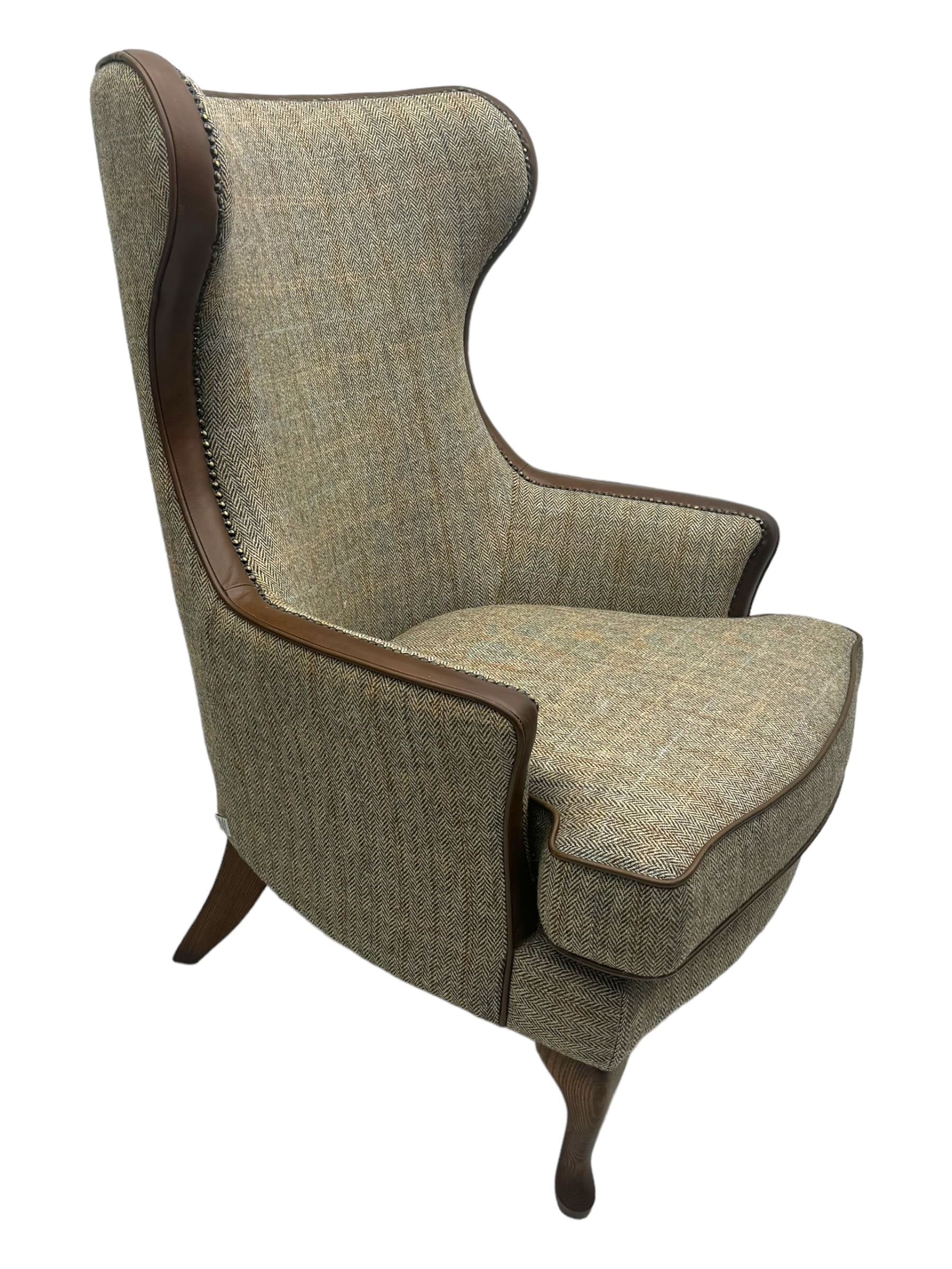 Wood Bros - contemporary wingback armchair, high back with curved wings upholstered in herringbone patterned fabric, accented with leather trim and brass nailhead studs, resting on cabriole front feet 