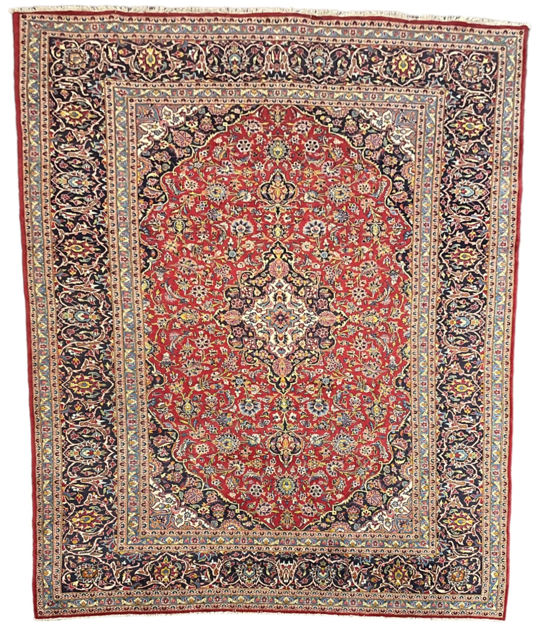 Persian Kashan crimson ground carpet, floral design central medallion surrounded by trailing leafy branches and stylised plant motifs, multi-band border with repeating floral design