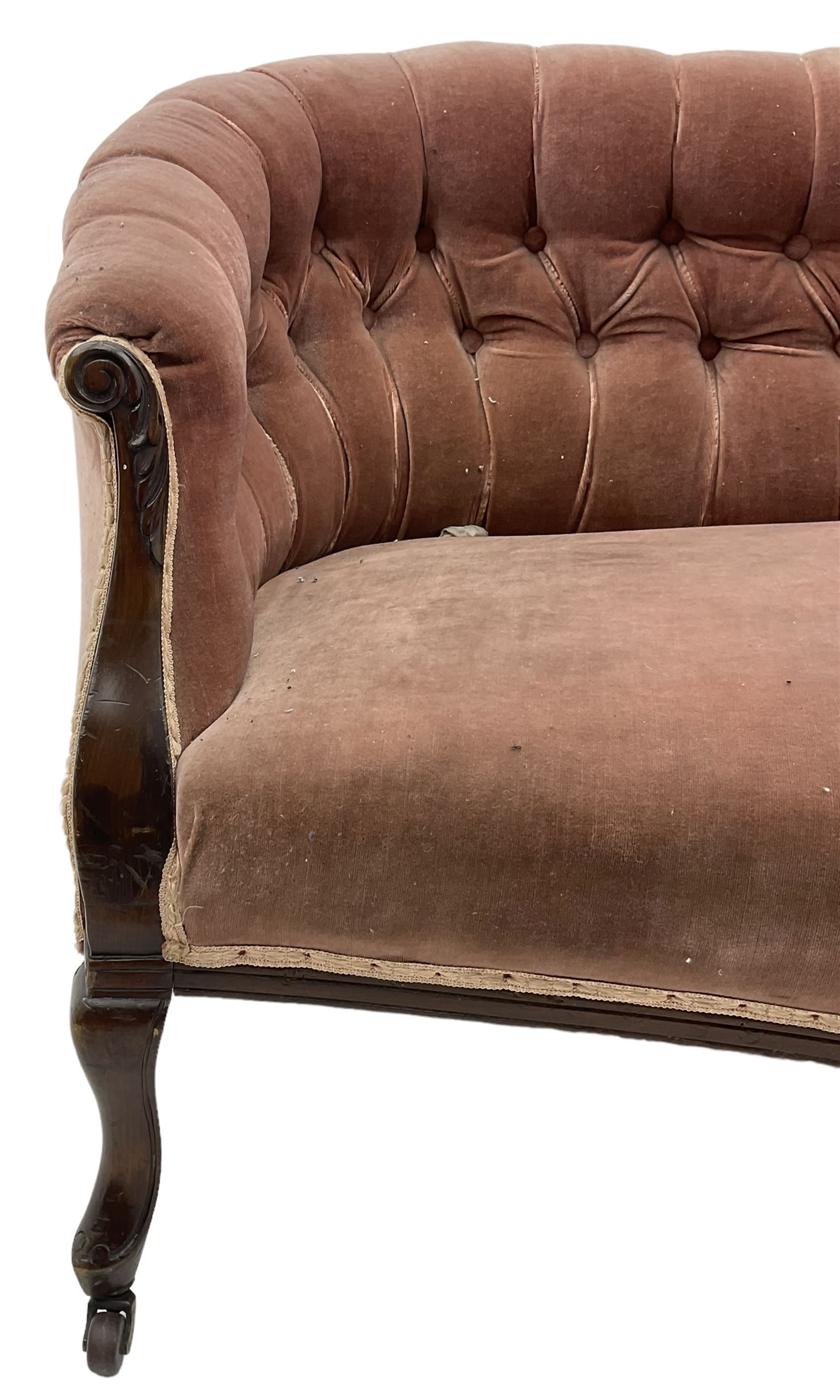 Late 19th century mahogany framed two-seat sofa, upholstered in buttoned pink fabric, on cabriole front supports, on castors 