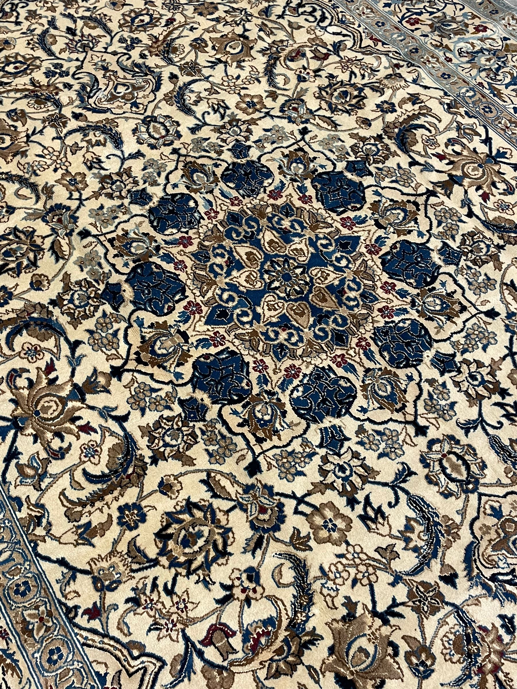 Persian ivory ground carpet, overall floral pattern with central rosette medallion, the field decorated with interlaced leafy branches and stylised plant motifs, guarded repeating border with repeating design