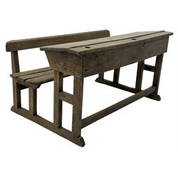 Victorian child's pine double school desk, the writing surface with two inkwells and two shelves underneath, integrated slatted bench seat raised on supports united by stretcher 