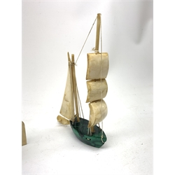 A Japanese carved ivory model of a sailing boat, surmounted by three carved figures (a/f), L22.5cm, together with a smaller sail boat with malachite hull and ivory sails and rudder, H18cm. 